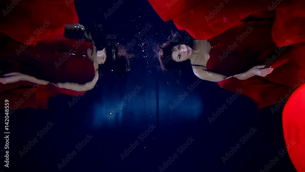girl floats underwater in red cloud material