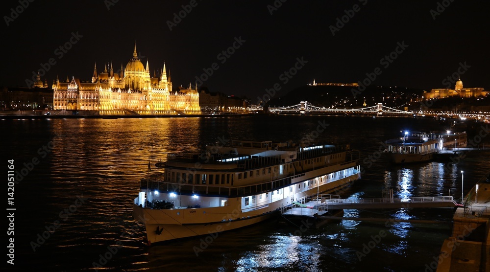 Night panorama of Budapest city centre with Parliament building, Chain Bridge, Buda Castle, Danube river and two boats