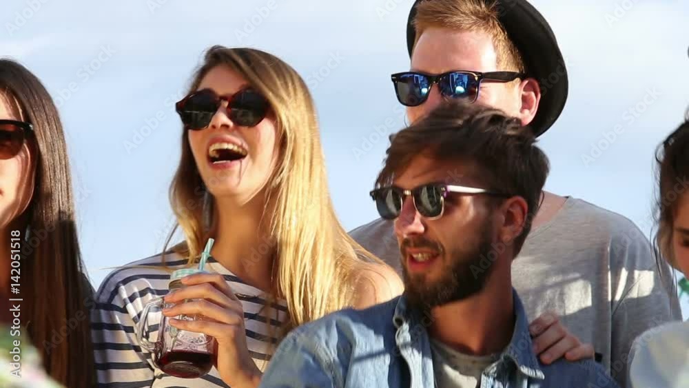 Close up of cheerful young friends dancing at rooftop party on sunny day, looking towards camera Close up of cheerful young friends dancing at rooftop party on sunny day, looking towards camera