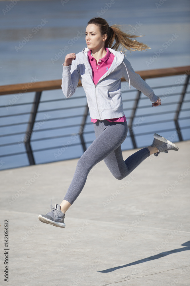 Morning exercise near the river. Young woman on recreation and jogging.
