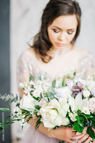 Beauty Portrait of bride wearing in wedding dress with voluminous skirt, studio photo. Young attractive bride with bouquet of flowers. Smiling beautiful young bride