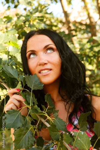 woman outdoors under green leaves. 