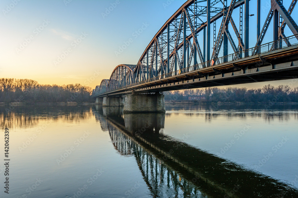 Jozef Pilsudski road bridge reflected in Vistula river in the morning. Torun, Poland. Europe.