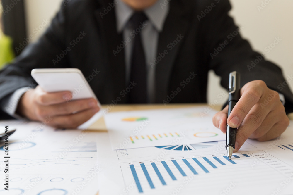 Businessman analyzing charts and graphs with smartphone. Businessman analyzing charts and graphs with smartphone.