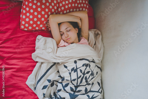 Девушка спит в кровати глубоким сном с ярким пастельным бельем