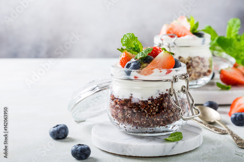 Gluten free breakfast with red quinoa, yogurt and berries in glass jar. Healthy super foods concept with copy space.