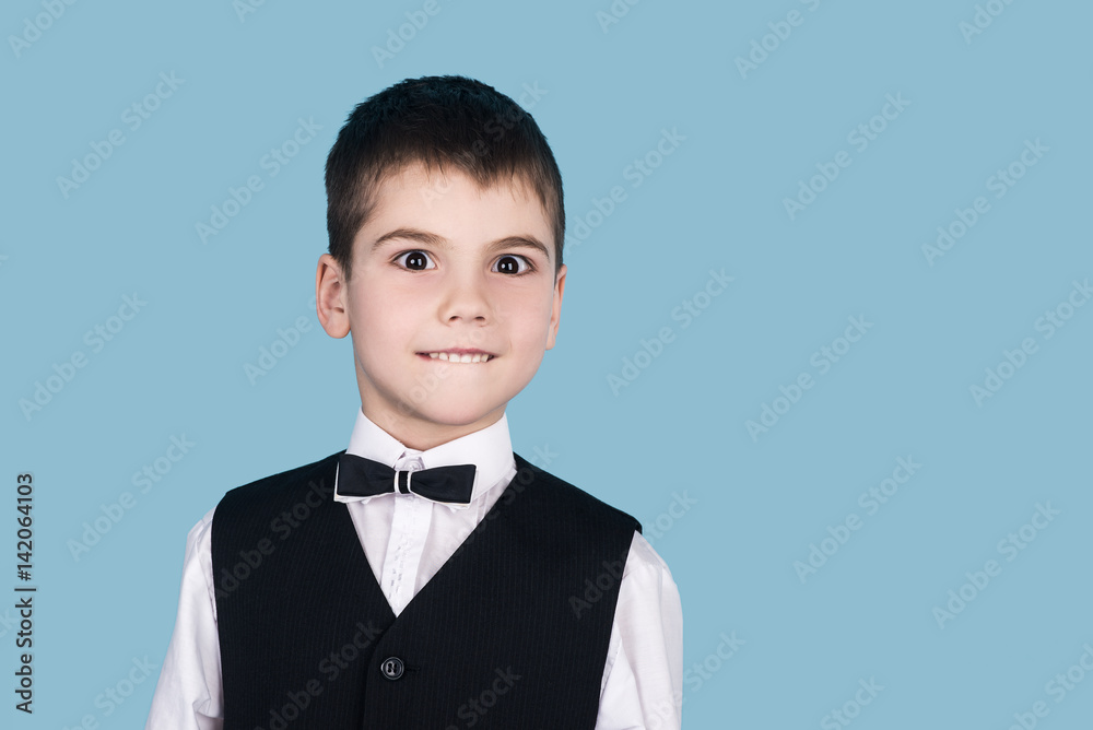 portrait of little business boy with big brown eyes, isolated on blue background, business suit wearing portrait of little business boy with big brown eyes, isolated on blue background, business suit wearing