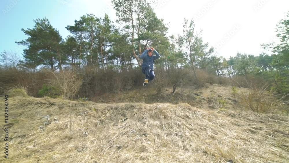 Young stunt shows hard tricks of parkour on the nature. Slowly