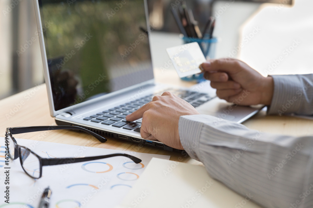 Businessman hand holding a Credit card intent to made a online payment with his computer laptop on his desk. Businessman hand holding a Credit card intent to made a online payment with his computer laptop on his desk.