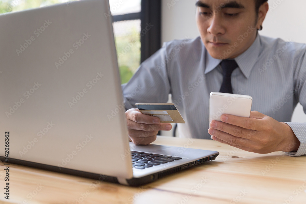 Businessman hand holding a Credit card intent to made a online payment with smartphone on his desk. Businessman hand holding a Credit card intent to made a online payment with smartphone on his desk.