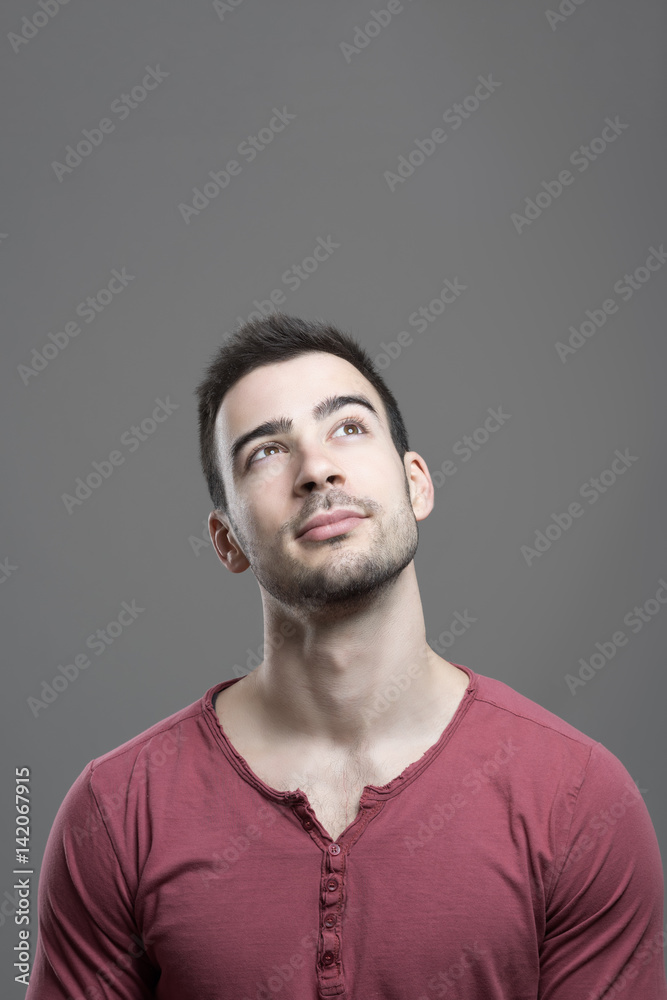 Obraz premium Concept of handsome young man looking up having an idea with empty copy space over gray studio background.