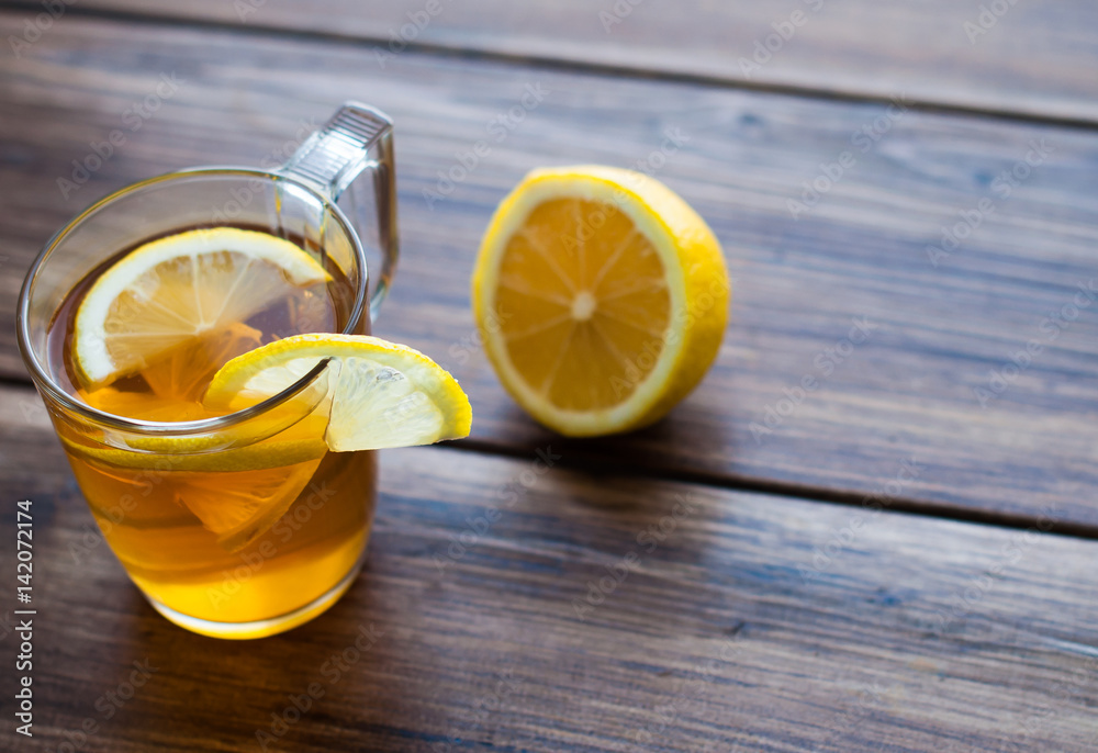Black tea with lemon in a glass cup on a wooden table. Top view, banner for a cafe. Black tea with lemon in a glass cup on a wooden table. Top view, banner for a cafe.