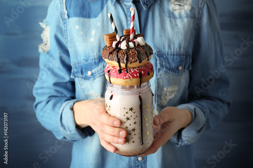 Girl holding milkshake with donuts and other sweets in jar photo