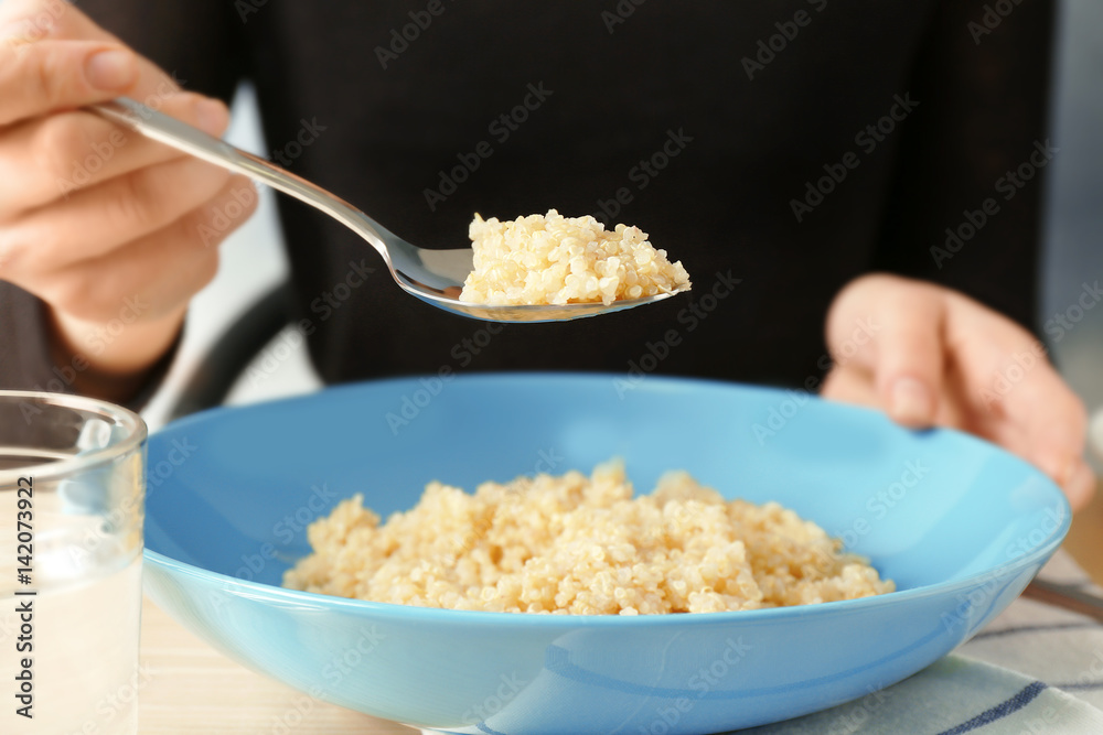 Woman eating quinoa porridge at kitchen table