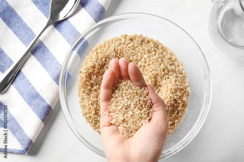 Handful of brown rice taken from glass bowl
