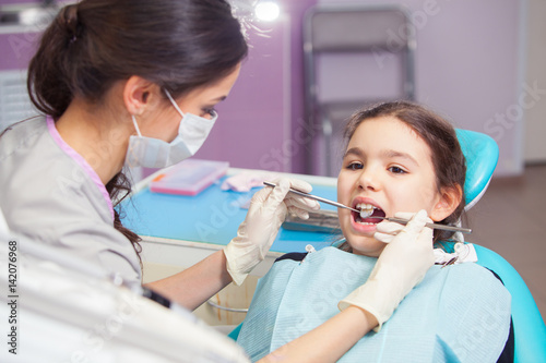 Close-up of pretty little girl opening his mouth wide during treating her teeth by the dentist