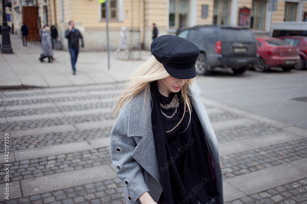 Young, hip and attractive blonde walking around the city, girl in a stylish hat and a gray coat. Pedestrian crossing