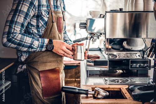 A man preparing cappuccino in a coffee machine.