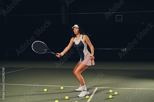 Female tennis player in action in a tennis court indoor. © Fxquadro