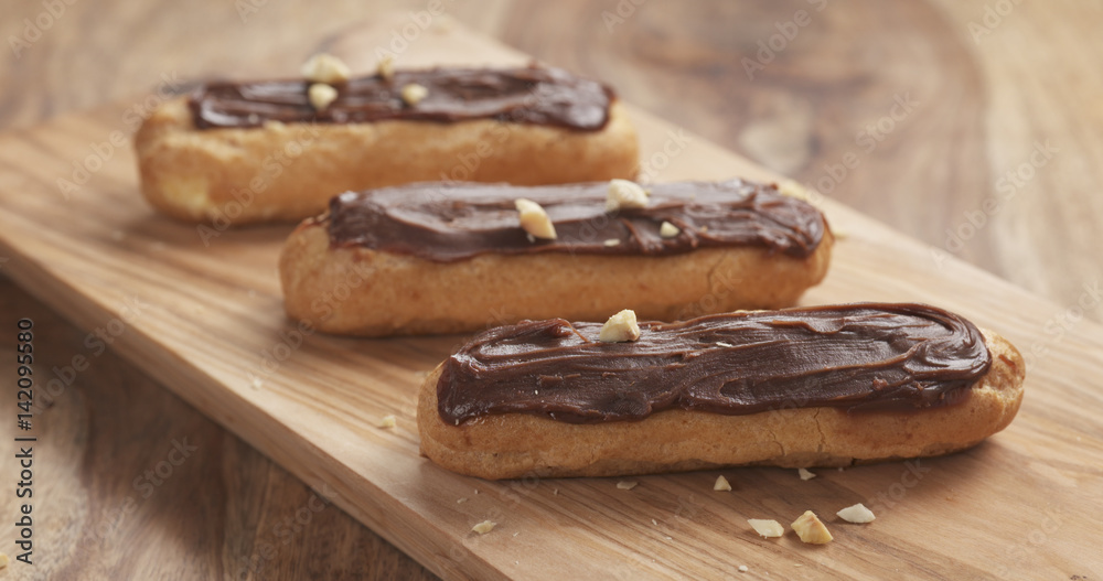 decorated eclairs with hazelnuts on wood board
