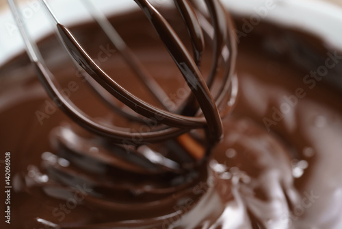 closeup of steel whisk in melted dark premium chocolate