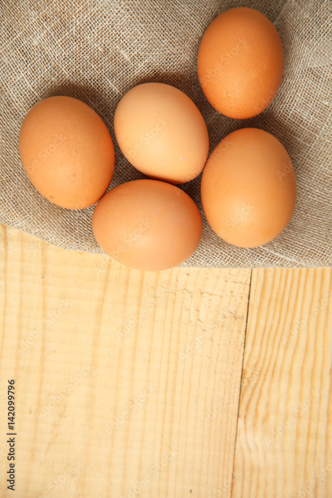 Raw organic brown eggs over linen napkin and rustic wooden background Raw organic brown eggs over linen napkin and rustic wooden background