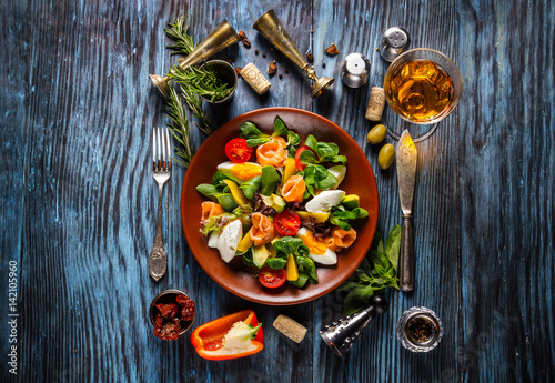 Delicious fresh salad with seafood on the old wooden background