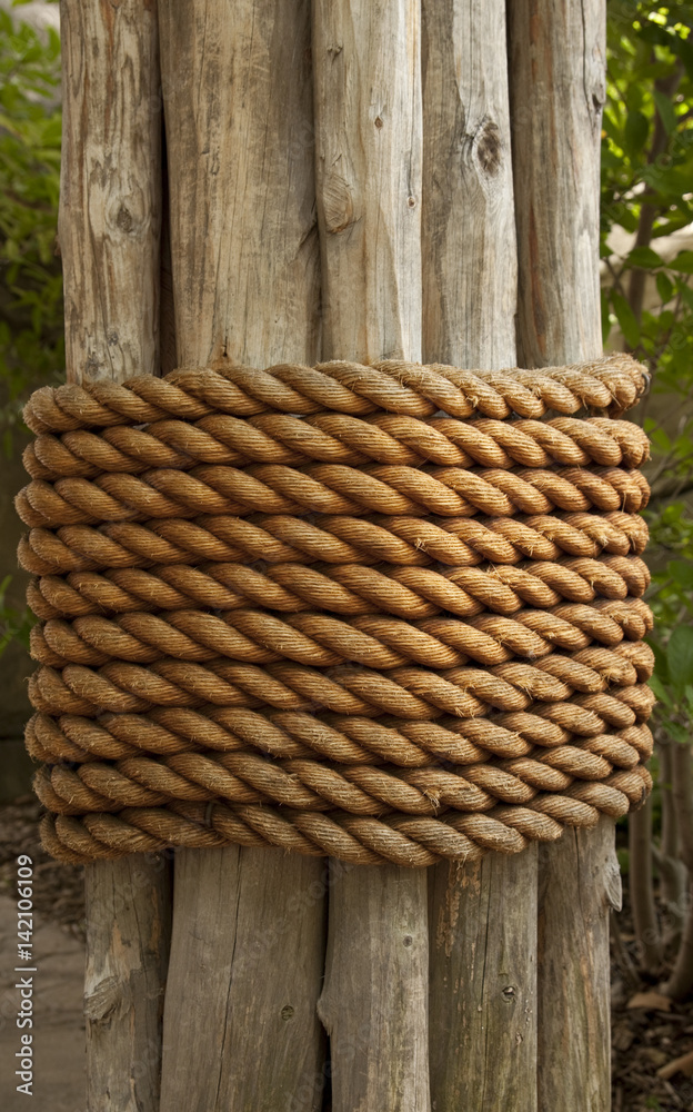 Large rope wrapped around wood poles Stock Photo
