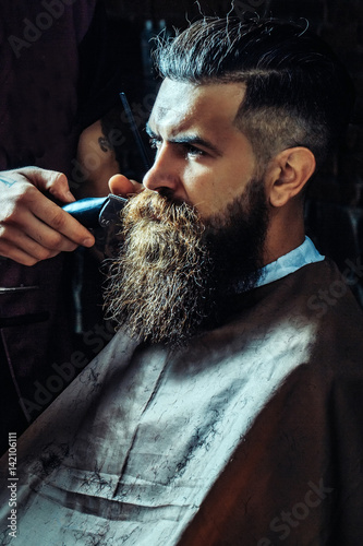 Fototapet Bearded man getting long beard haircut with clipper