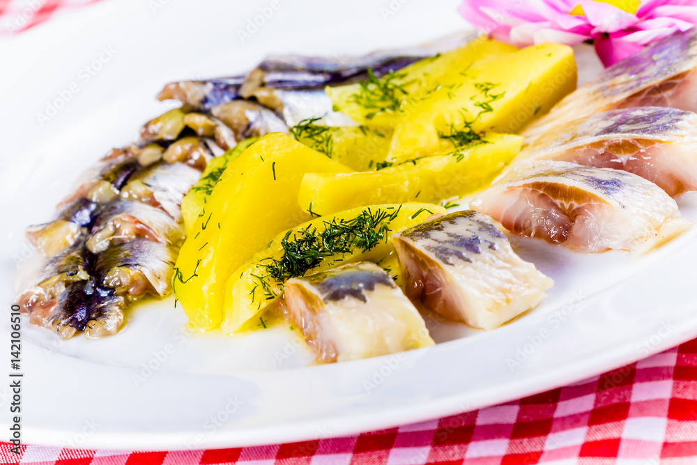 Salted herring and mackerel with boiled potatoes on a white plate