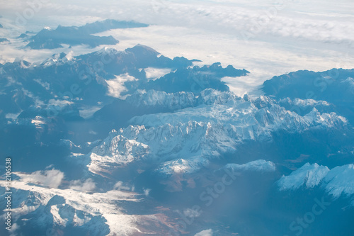 Idyllic snowy mountain peaks under clouds from plane