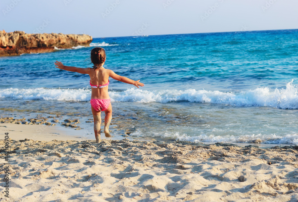 Fototapeta premium Happy Cute Little Girl running on the coast of warm Sea at Summer Sunset