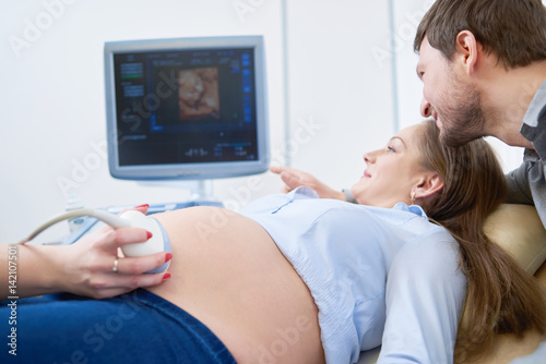 Photo Loving couple attending doctor for pregnancy ultra sound procedu