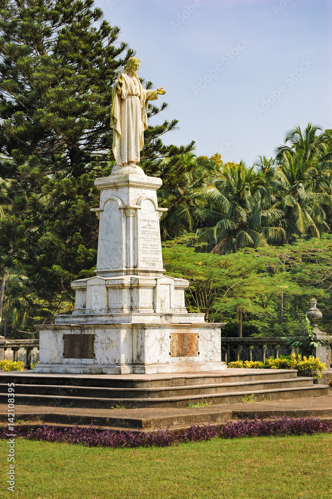 Statue of Jesus near Catedral de Santa Catarina, known as SE Cathedral surrounded by palm trees in Old Goa, India