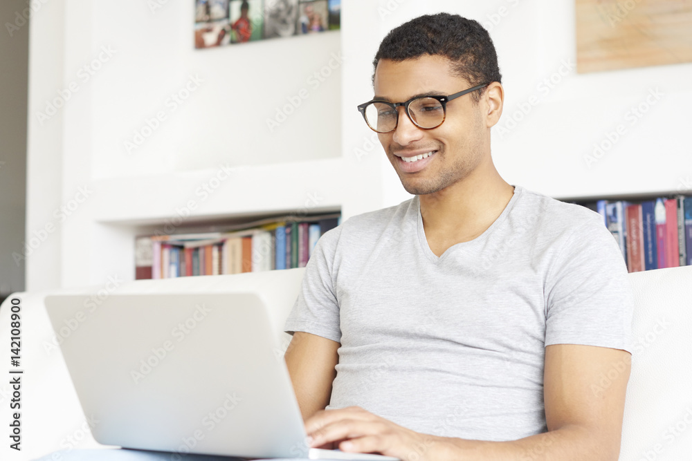 Managing your business from home. Shot of a young Afro American man using laptop while working at home.
