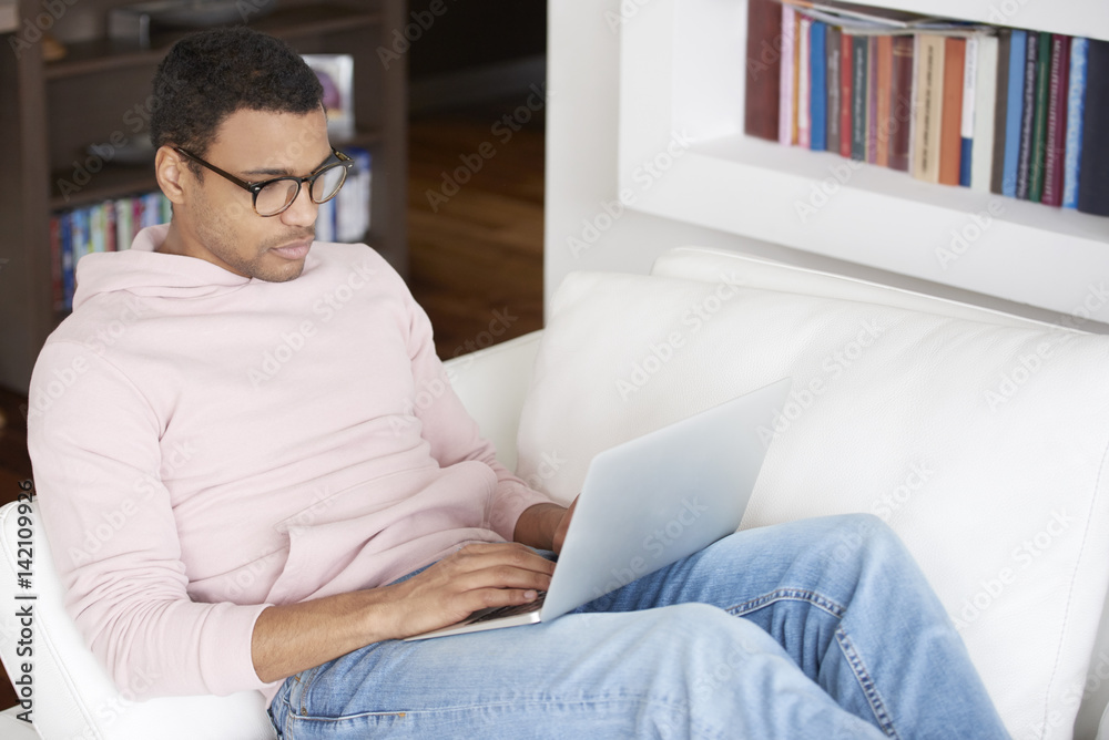 Managing your business from home. Shot of a young Afro American man using laptop while working at home. Managing your business from home. Shot of a young Afro American man using laptop while working at home.
