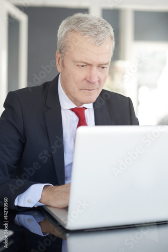 Senior businessman in the office. Shot of a financial managing director working on laptop and analysing financial data.