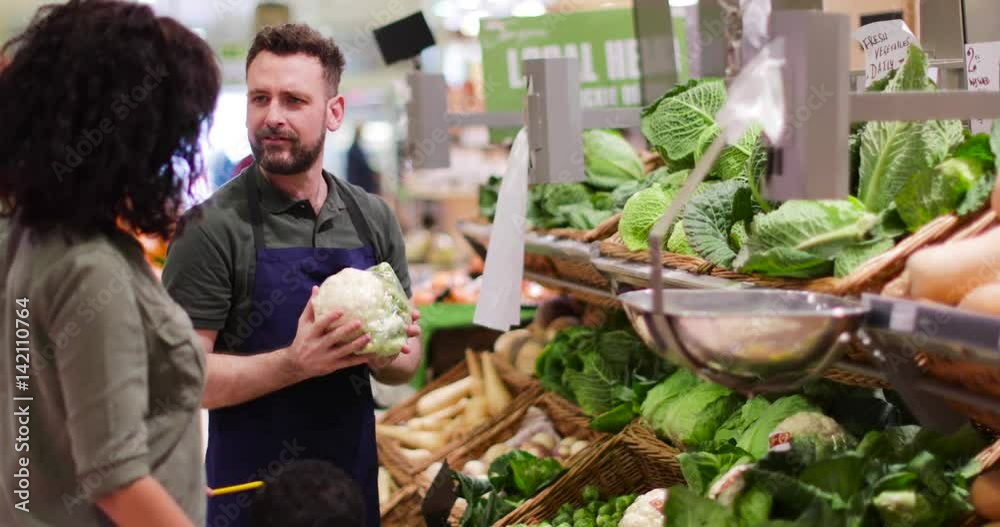 Shop assistant in grocery store helping shoppers Shop assistant in grocery store helping shoppers