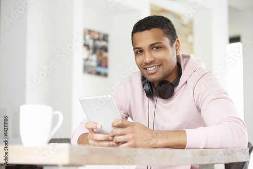 Enjoy music. Shot of a handsome young Afro American man using his laptop and listening music while working at home. 