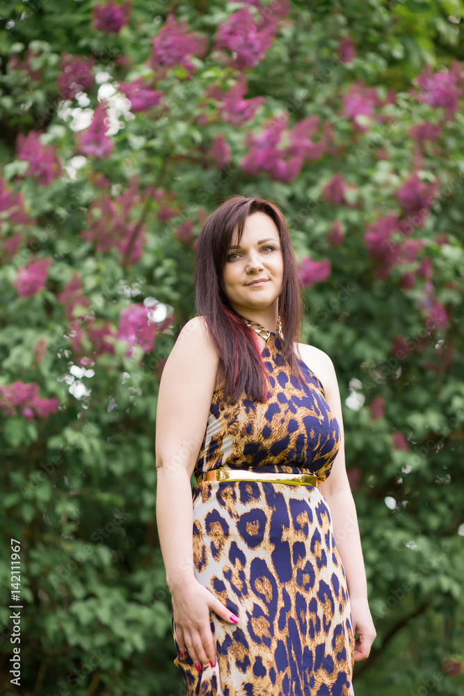 Portrait of a sexy sensual beautiful brunette girl with long hair in leopard yellow-black dress walking in the park Portrait of a sexy sensual beautiful brunette girl with long hair in leopard yellow-black dress walking in the park