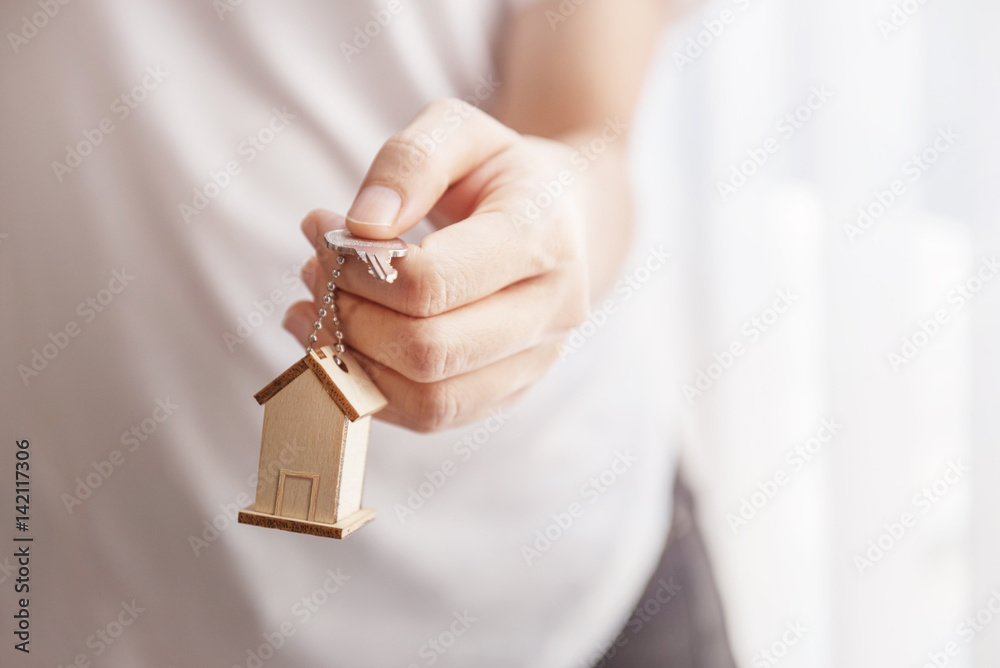 Obraz premium Female hand holding key house shaped keychain.
