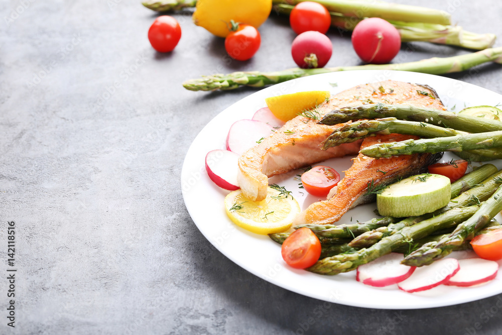 Steak of salmon with asparagus and vegetables on grey wooden table Steak of salmon with asparagus and vegetables on grey wooden table