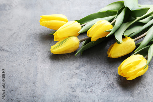 Bouquet of yellow tulips on grey wooden table