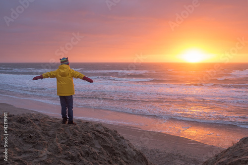 Child observing sunset on a winter beach in Texel, the Netherlands. photo