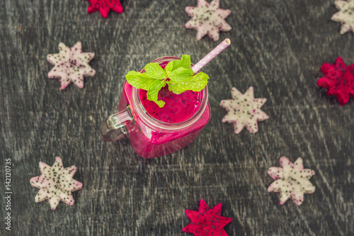 Pieces of sliced dragon fruit in the form of a star and smoothies from a dragon fruit on an old withered background photo