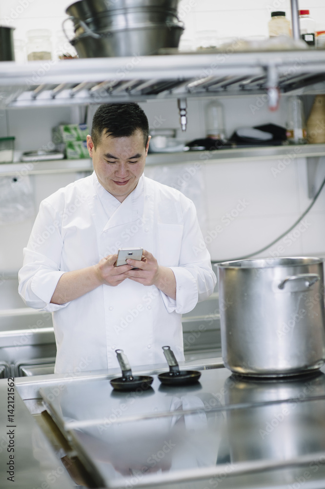 Chinese cook speaks with smartphone and notebook Chinese cook speaks with smartphone and notebook