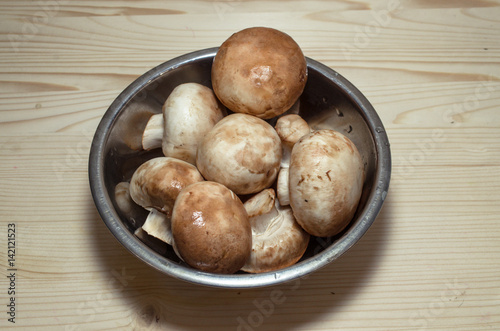 champignon mushrooms in bowl on wooden background