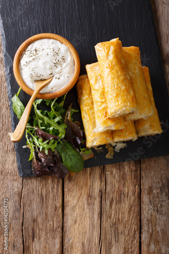 Filo rolls with meat, eggs and greens close-up and yogurt. Vertical top view photo