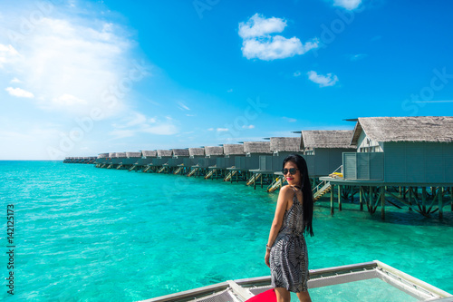Portrait of happy young woman at beautiful water villa at Maldives island. Travel and Vacation. Outdoor shot. © jannoon028