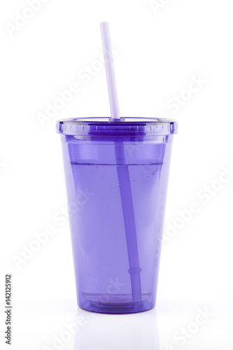 Purple plastic travel cup with straw on a white surface. Isolated on white background.